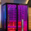 Vatra 3-4 person infrared sauna showcasing its sleek black titanium frame and hot pink chromotherapy lighting