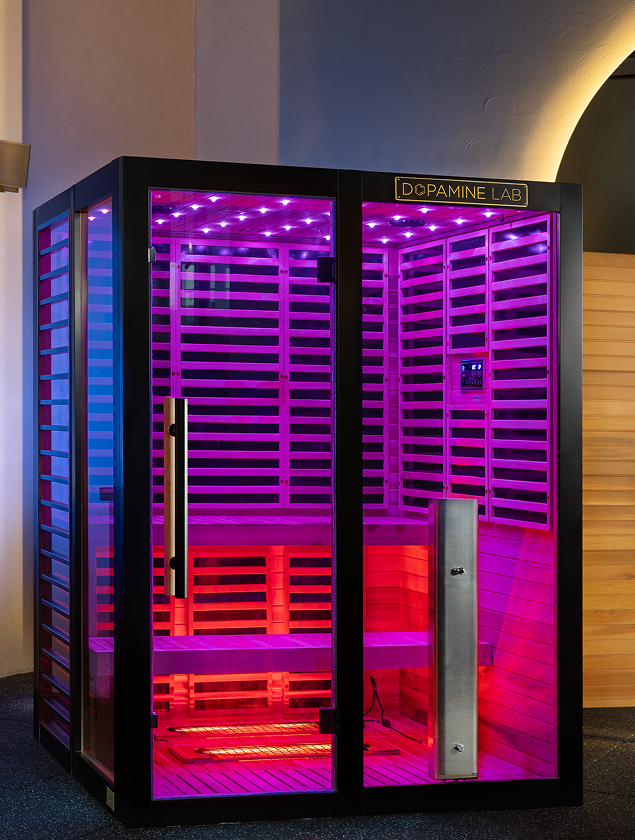 Vatra 3-4 person infrared sauna showcasing its sleek black titanium frame and hot pink chromotherapy lighting